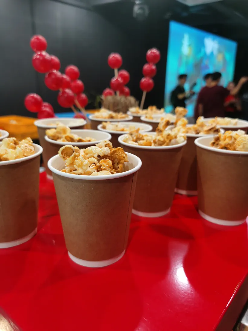 Cups of freshly made popcorn lined up on a serving table at an event