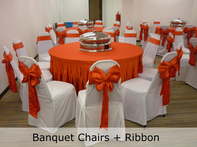 Banquet chairs dressed in covers with red ribbons