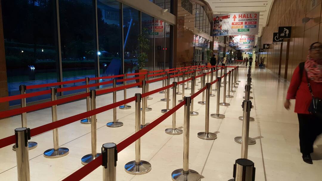 Row of black retractable-belt queue stanchions forming a line at an event entrance